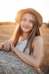 Poster - Smiling girl in the rural field with a setting sun on the background. Portrait of a positive young female