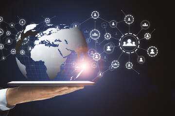Aufkleber - Hand with a tablet holding the globe icon with muptiple small application icons near it on a dark background. Worldwide web and social communication concept