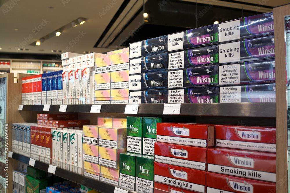 Fotografia do Stock Various brands of tobacco on store shelf in Changi  Airport Terminal 2. Tobacco use is a risk factor for many diseases,  especially those affecting the heart, liver, and lungs
