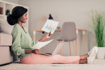 Poster - Full body profile side photo of young african woman sit floor home analyze documents project report laptop