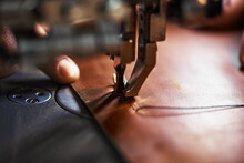 Working Process Of Leather Craftsman. Tanner Or Skinner Sews Leather On A Special Sewing Machine, Close Up.worker Sewing On The Sewing Machine
