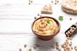 Bowl of homemade hummus on light background with copyspace.