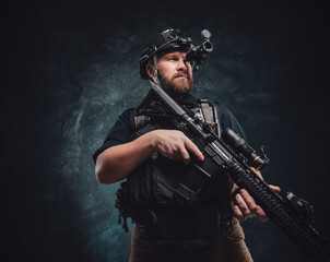 Wall Mural - Martial guy looks in night vision device holding his rifle in dark background