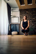 © chika_milan - Calm middle-aged woman practicing yoga at home.