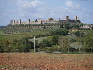 Wall Mural - Panorama of Monteriggioni Castle with circular perimeter walls with 14 towers lying on the top of a hill surrounded by the countryside and olive groves