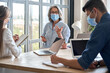 © insta_photos - Senior older educator working with computers in office with team wearing medical masks during covid lockdown.Adult experienced business woman is holding meeting with female assistant and male manager.