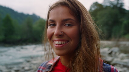 Woman looking at camera on mountain landscape. Girl touching hair with hand