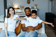 © Kanstantsinzzz - Loving black family relaxing at sofa in the morning, happy mixed race parents laughing cuddling having fun with cute little kid child son playing enjoying moments together. High quality photo