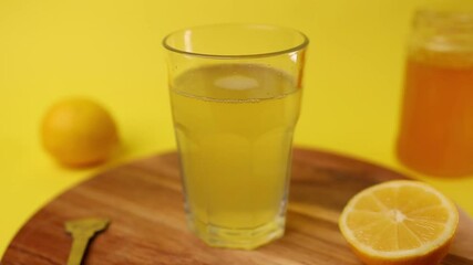 Wall Mural - A person's hand placing a glass of fresh and cold lemonade on a wooden board