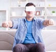 © Elnur - Man with virtual reality glasses playing at home