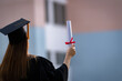 © EduLife Photos - A young happy Asian woman university graduate in graduation gown and mortarboard holds a degree certificate celebrates education achievement in the university campus.  Education stock photo