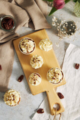 Sticker - Top view of delicious carrot cupcakes with whipped cream and topping from nuts