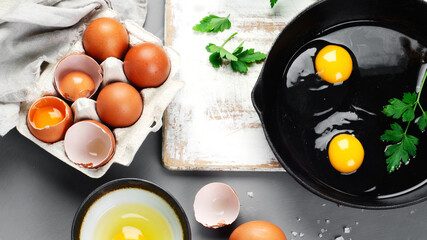 Wall Mural - Raw eggs in pan with herbs and seasoning on gray background, prepared food for breakfast.