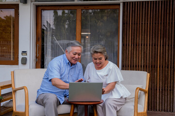 Asian elderly family relaxing together at home. Senior couple laptop computer video call to family or doctor. Retirement family husband and wife enjoy leisure activity lifestyle at home with happiness