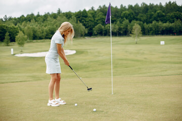 Wall Mural - Beautiful girl playing golf on a golf course