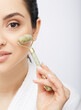 © Peakstock - Face jade roller. Cropped half face of a Hispanic woman with jade or stone roller for anti-aging procedure