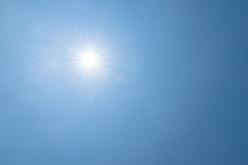 shining sun on clear blue sky. lens flare of sunlight on blue sky background. bright sun on blue sky