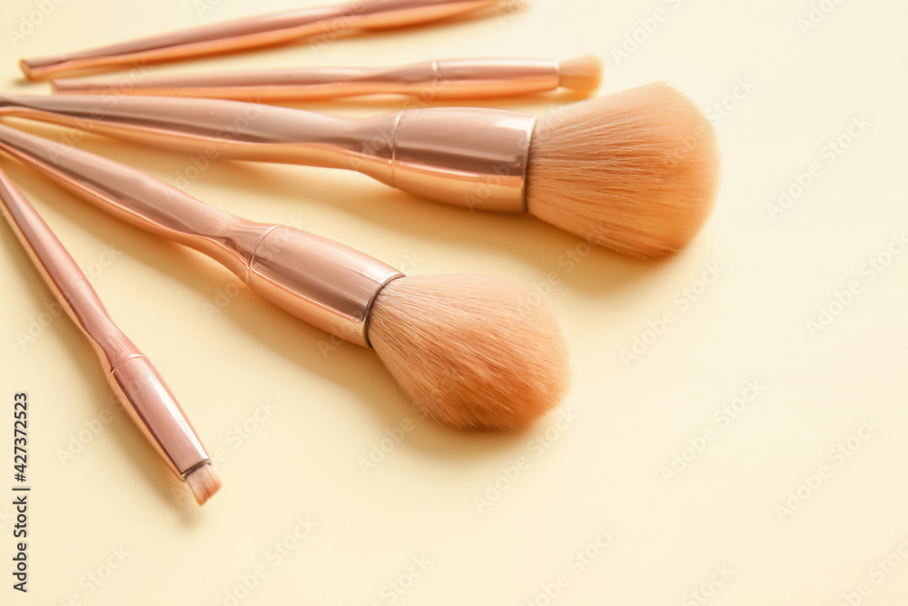 Stylish makeup brushes on color background