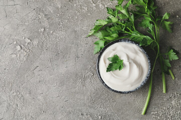 Bowl of tasty sour cream and herbs on grunge background