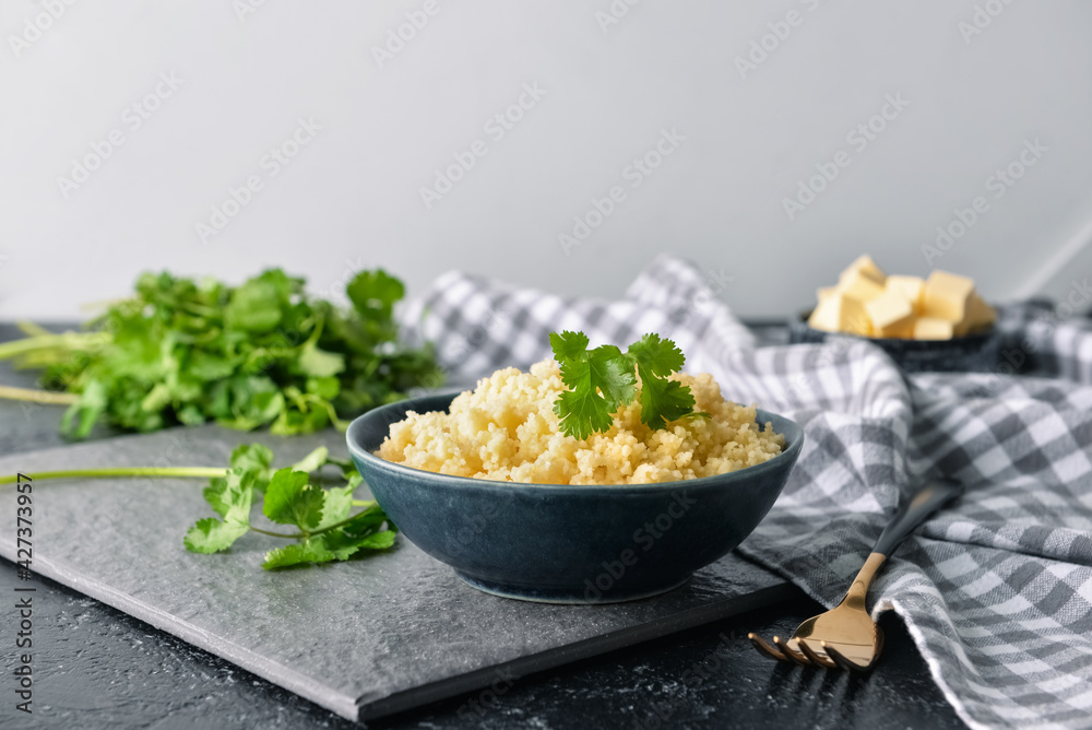 Bowl with tasty couscous and cilantro on table