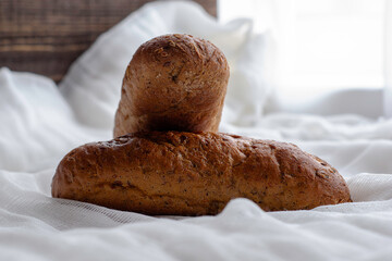 two freshly baked rye bread rolls on a white cloth napkin