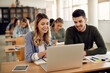 © Drazen - Happy university students using laptop while learning in the classroom.