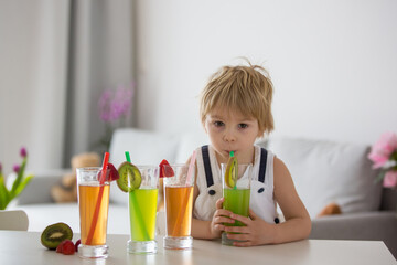 Canvas Print - Cute toddler child, blond boy, drinking freshly made fruit juice at home