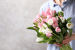 Woman holding bouquet of tulips against beige background, closeup. Space for text