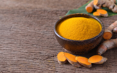 Canvas Print - Turmeric powder in a wooden bowl and fresh turmeric (curcumin) on wooden background,copy space.