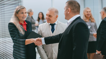 Poster - smiling businesswoman meeting colleagues with a handshake.