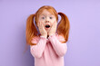 © alfa27 - nice little surprised girl with ginger red hair and freckles, stands over purple background touching cheeks