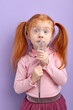 © alfa27 - Surprised caucasian redhead girl holding magic wand, looking at camera, pastel purple studio wall, copy space
