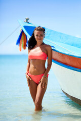 Wall Mural - Sexy girl in red swimsuit posing at the tropical beach near to boat