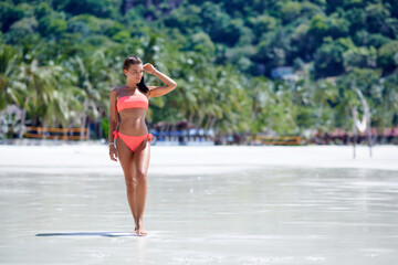 Wall Mural - Sexy girl in red swimsuit posing at the tropical beach