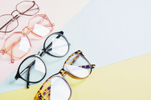 Multiple Eyeglasses On A Multicolored Background Of Pastel Colors, Geometric Background, Pink Yellow And Light Blue Colors, Trendy Eyeglass Frames