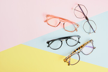 Wall Mural - multiple eyeglasses on a multicolored background of pastel colors, geometric background, pink yellow and light blue colors, trendy eyeglass frames