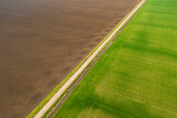 Fototapeta Tęcza - aerial view of an old country road between agricultural fields in spring