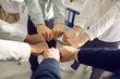 © Studio Romantic - Teamwork, teambuilding, responsibility and equal opportunities. Close up top view of interracial business people team or diverse student hand holding together bumping fists in circle as unity symbol