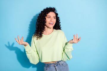 Poster - Photo of cheerful positive lady raise palms look empty space wear green sweatshirt isolated blue background