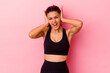 © Asier - Young sport Indian woman isolated on pink background covering ears with hands trying not to hear too loud sound.