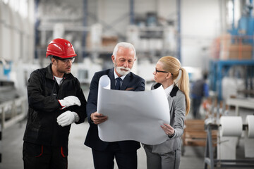 Architects and worker working on project. Colleagues working in factory.