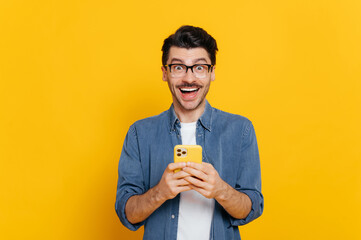 stunned shocked stylish guy with eyeglasses, using smartphone, chatting online, writing message, bro