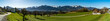 Panorama Aussicht über das Tal auf die verschneiten Berge von Brand und Nenzing. Wiesen mit Frühlingsblumen und Bäumen an einem sonnigen Tag. Walgau im besten Licht. Vorarlberg