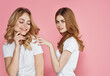 © SHOTPRIME STUDIO - Two sisters in white t-shirts caring friendship pink background joy