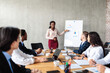 © Prostock-studio - Businesswoman Pointing At Charts On Blackboard During Corporate Meeting Indoor