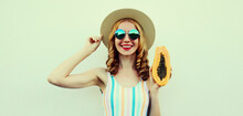 Summer Portrait Of Happy Smiling Young Woman With Papaya Wearing A Straw Hat, Sunglasses On A White Background
