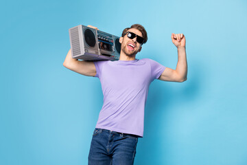 Sticker - Photo portrait of young man in black sunglass keeping boombox dancing isolated on pastel blue color background