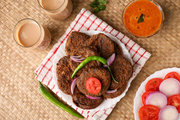 Wall Mural - Many beef or chicken cutlet, tomato sauce Kerala South India. hot and spicy tea time snack on white plate, dark black background. fried meat of veal, mutton or fish. Top view Indian snack non veg food