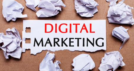 Fototapete - DIGITAL MARKETING written on white paper on a light brown background.