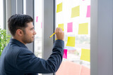 Fototapeta Nowy Jork - Business man is working and brainstroming in the meeting room with colleauge. Using agile methodology and do business model canvas . Colorful sticky notes on the wall are posted for new idea